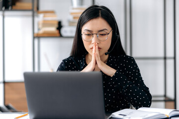 Asian young woman with glasses, office worker, manager or entrepreneur, sitting at a work desk in...