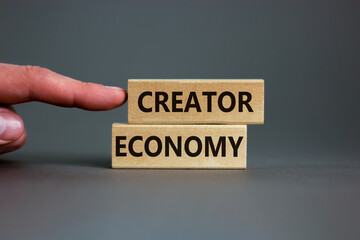 Creator economy symbol. Wooden blocks with words Creator economy on beautiful grey background, copy space. Businessman hand. Business and creator economy concept.