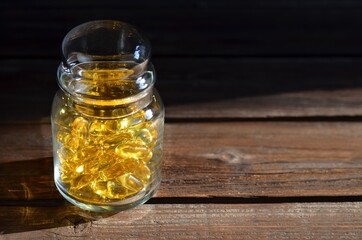 Glass jar with dietary supplements in transparent yellow capsules