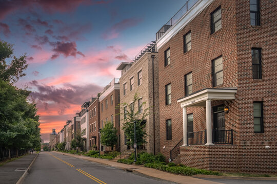 Newly built multi story luxury single family homes lining up next to an old railway station and coal tower on Water street in Charlottesville Virginia with dramatic colorful sunset sky