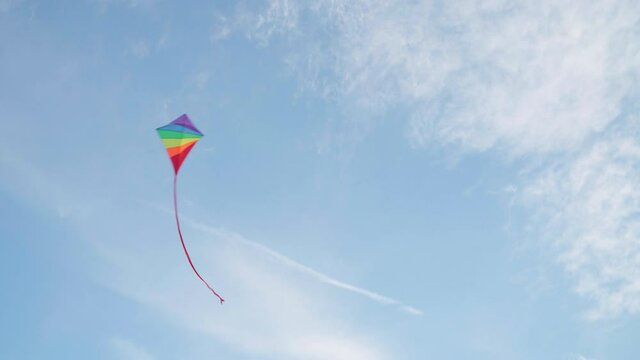 4K Footage of a flying multicolored rainbow style new kids toy in the blue sky. Active outdoor concept image.