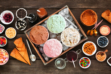 Summer ice cream buffet with a mixture of flavors and sweet toppings. Top view table scene on a...