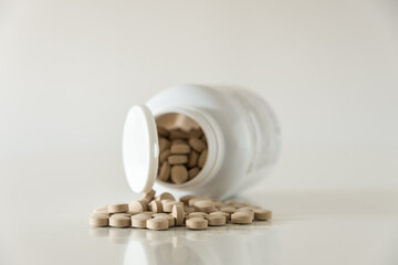 Pills in white bottle on white background close up with copy space