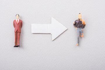 Top view of an arrow between two differently dressed figurines