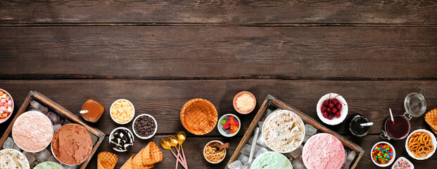Summer ice cream buffet with an assortment of flavors and sweet toppings. Top view border on a dark...