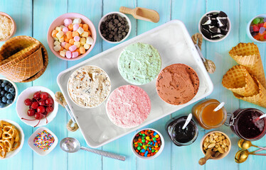 Summer ice cream buffet with a variety of flavors and sweet toppings. Overhead view table scene on...