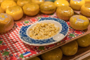 Traditional Dutch gouda cheese cut into small squares on a porcelain plate, surrounded by cheese cubes.