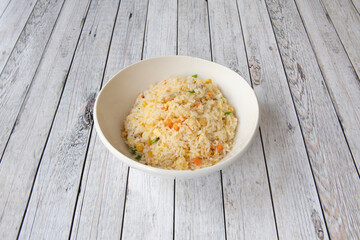 White bowl of rice three delights cooked in a Chinese restaurant with white tables