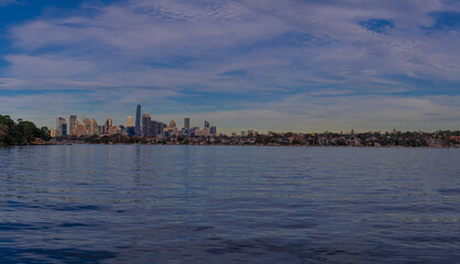 Fototapeta premium Panoramic view of Sydney Harbour and City CBD Skyline of NSW Australia. The beautiful light skies at sunset lovely blue waters 