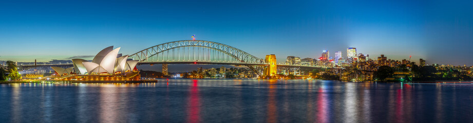 Fototapeta na wymiar Panoramic night view of Sydney Harbour and City Skyline of circular quay the bridge nsw Australia. bright neon lights reflecting off the water