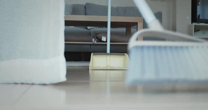 Woman cleaning and sweeping dust on the floor with a broom