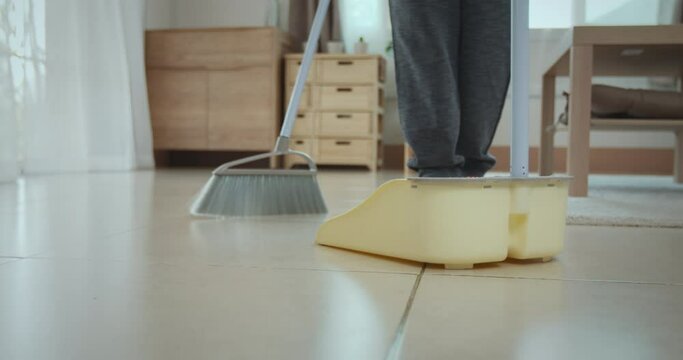 Woman cleaning and sweeping dust on the floor with a broom
