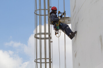 Fototapeta premium Male worker rope access inspection of thickness storage tank industry