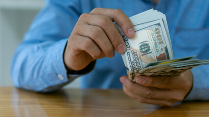 Asian businessman counting banknotes on wooden table Concept of counting money, salaries, payments to employees in a company office.