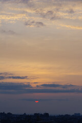 Fototapeta premium 兵庫県神戸市東灘区の高層マンションの上層階からの夜明け。大阪生駒山から太陽が昇り、あたりはオレンジ色に染まり、ビル群がシルエットで浮かぶ。
