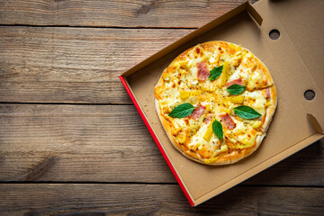 Pizza in box, pizza homemade italian food style Tasty pizza cheese ham and pineapple fruit. Top view