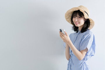 スマートフォンを使う麦わら帽子の女性
