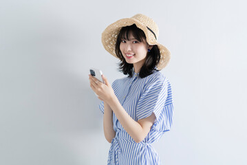 スマートフォンを使う麦わら帽子の女性