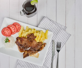 Delicious and succulent Beef steak meat with accompaniments: French fries, tomato and rice