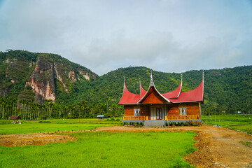 Minangkabau house/Rumah Gadang in a beautiful landscape view of Harau Valley with mountains valley and grass view, West Sumatra, Indonesia. Beautiful Minangkabau, Indonesia Landscape.
