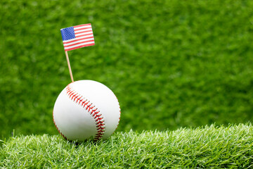 Baseball is on green grass with flag of America