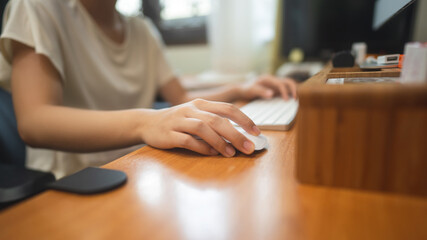 Woman hand holding wireless mouse computer for working online on wooden table.