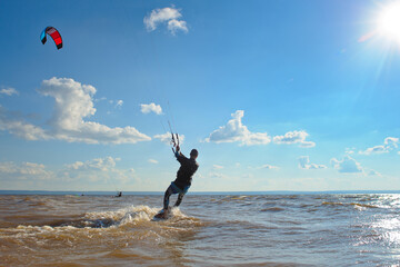 Kiteboarder surfing waves with kiteboard on a sunny summer day.