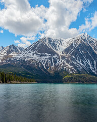 Fototapeta na wymiar Stunning landscape beautiful view of Kathleen Lake in Yukon Territory, northern Canada with calm, pristine lake below snow capped mountain peaks in May, spring time. 