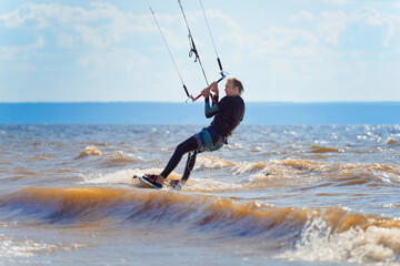 Kiteboarder surfing waves with kiteboard on a sunny summer day.