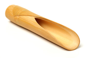 Wooden scoop over dry green tea leaves