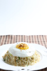 wok garlic olive fried rice with small silver fish seafood, fried egg and vegetables on white plate asian halal menu