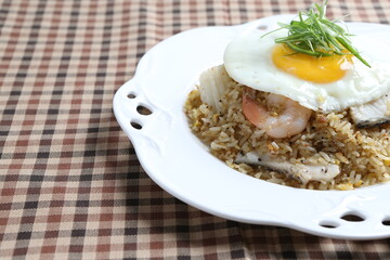 wok garlic fried rice with mixed seafood fish, prawn, squid, octopus, fried egg and vegetables on white plate asian halal menu