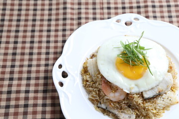 wok garlic fried rice with mixed seafood fish, prawn, squid, octopus, fried egg and vegetables on white plate asian halal menu