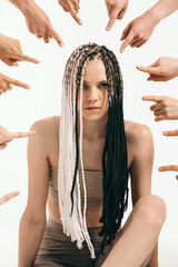 The girl is condemned by society. Original girl with African pigtails. Everyone points the finger...