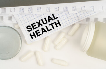 On the table is an open jar of pills and a sheet of paper with the inscription - SEXUAL HEALTH