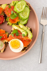 Healthy tasty breakfast, sandwiches with avocado and salmon, cucumbers and tomatoes, radishes and microgreens of peas with boiled egg