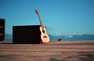 Ukulele guitar on wooden table over the sky