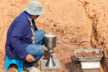 Worker using equipment for testing laboratory field density test sand cone method and soil density test of road under the construction.Soil field density test sand cone method calculation . - obrazy, fototapety, plakaty