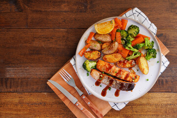 Homemade Grilled Salmon Steak with Broccoli, Potatoes, Carrots in a plate on a wooden table