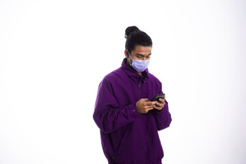 Covid19, the concept of health care and medicine. A young man reading a news on his phone in a face mask, supporting social distance