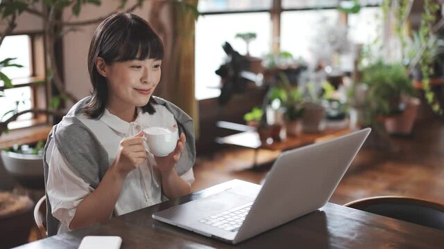 暖かい雰囲気の空間で、ノートパソコンの画面を見る女性
