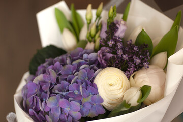 Beautiful wedding bouquet of lilac, white tulips, blue hydrangeas, white ranunculus and eucalyptus in white, delicate packaging