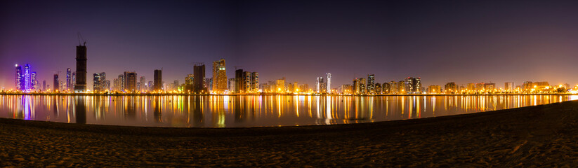 Fototapeta premium Beautiful panoramic shot of Sharjah Skyscraper or Skyline. A view from Al Mamzar Beach Dubai at night.