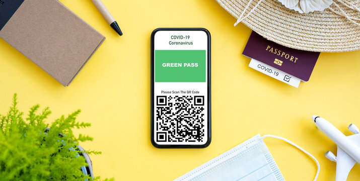 Flat lay, a smartphone with a Green Pass is arranged on a yellow background with travel accessories.