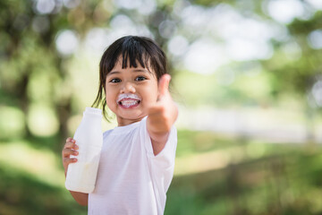 Cute asian little child girl is drinking a milk, soft focus