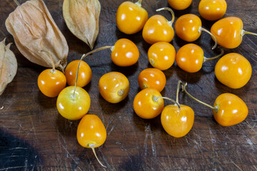 Fresh winter cherries, Physalis, Cape gooseberry, Aguaymanto, Uvilla, Peruvian fruit on a wooden base.
