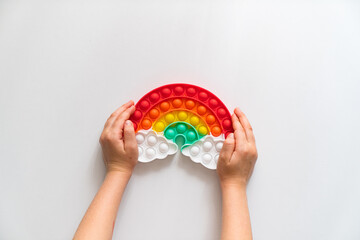 Hand plays with a multi-colored anti-stress toy in the shape of a rainbow. 