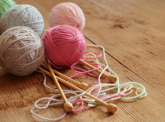 Colorful balls of yarn and knitting needles on wooden background