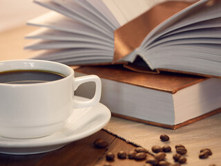 Education learning concept with opening book or textbook in old library, stack piles of literature text academic archive on reading desk and aisle of bookshelves in school study class room background