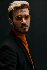 Fototapeta premium portrait of handsome blond man in jacket orange sweater on dark background 